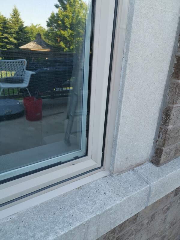 Close-up of a completed, flawlessly smooth and tooled black commercial-grade sealant bead on a beige window frame in Burlington.