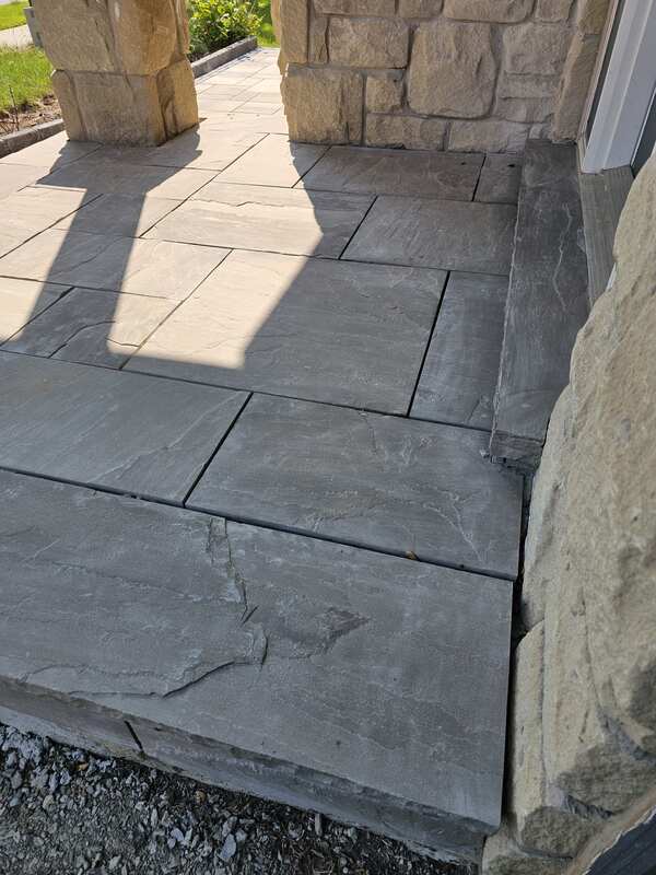 View of grey flagstone porch steps with clean, empty joint channels following full mechanical breakout and substrate preparation.