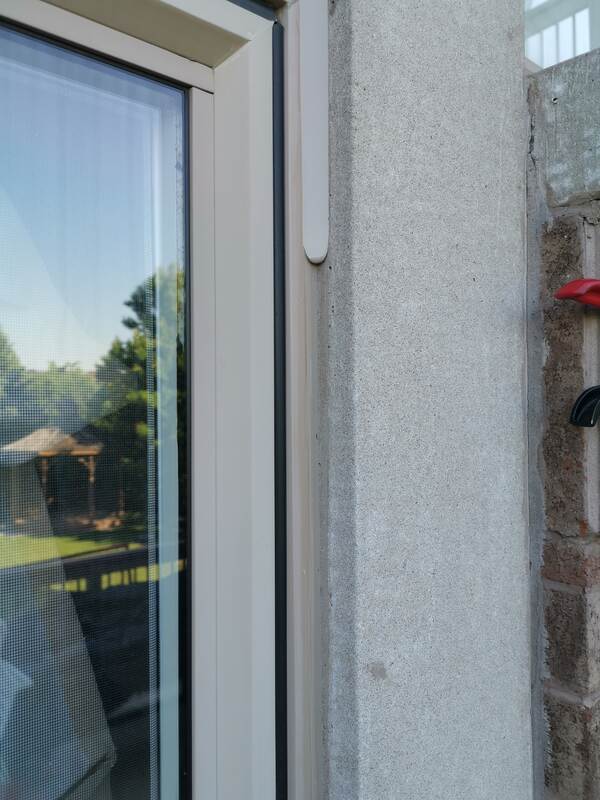 Close-up of a freshly applied, wet black commercial sealant bead injected into a residential window joint perimeter in Burlington.