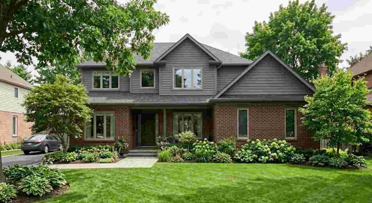 Clean exterior window frames on a brick home surrounded by green landscaping protected by professional caulking in Burlington Ontario.