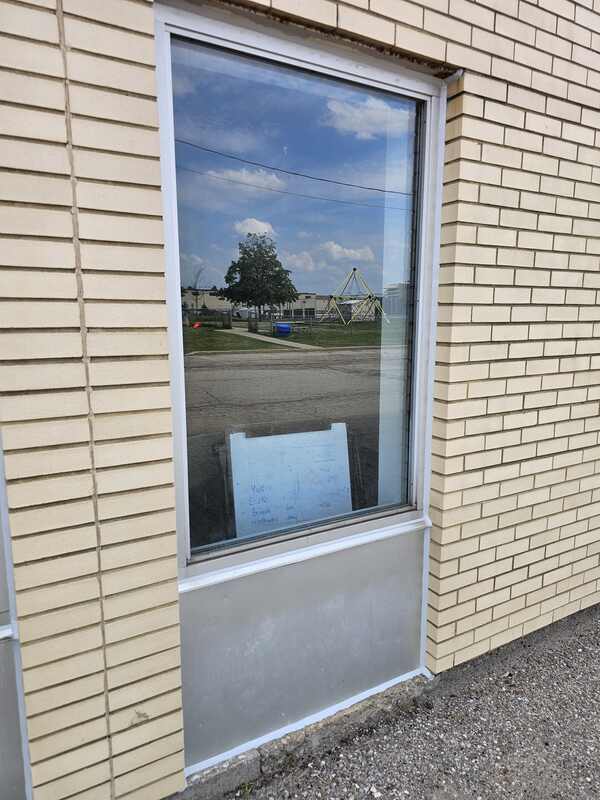Full view of a completed, flawlessly weatherproofed commercial window unit installed in a beige brick facade with clean white sealant joints.