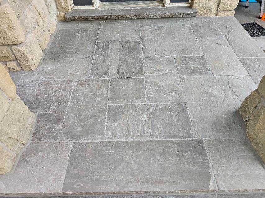 Top view of completed, flawlessly sealed grey natural flagstone porch steps with clean, texturized matte grey sealant joints that replicate masonry grout.