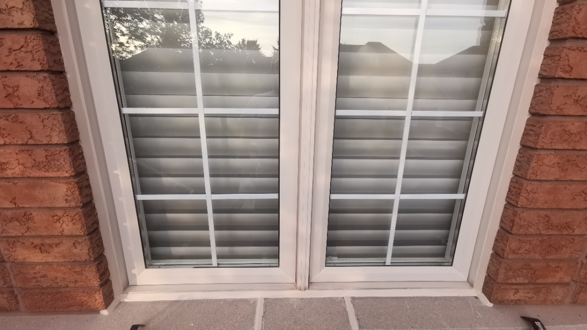 Professionally sealed exterior white vinyl window frame on a red brick home by Proper Caulking in Burlington Ontario.