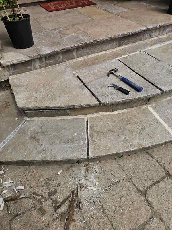 Close-up of natural stone flagstone steps under construction with clean, hollowed-out joint channels following the mechanical extraction of old, cracked cement mortar.