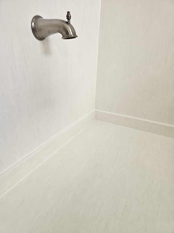 A razor-thin, perfectly dry-tooled white silicone sealant bead applied smoothly around a brushed nickel tub spout and along an acrylic bathtub surround joint.
