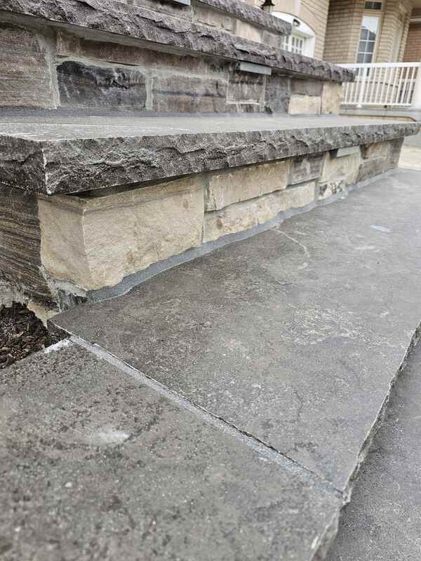 Looking down a completed multi-tiered exterior concrete staircase showing a flawless grey sealant bead bonding stone step treads to masonry risers.