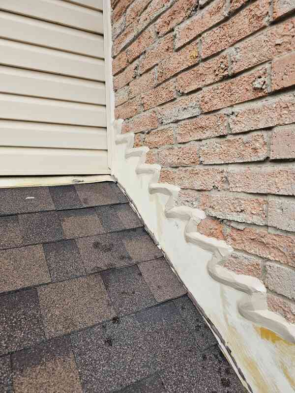 Completed exterior caulking showing a crisp grey commercial sealant bead bonding a metal roof flashing track to a red clay brick wall.