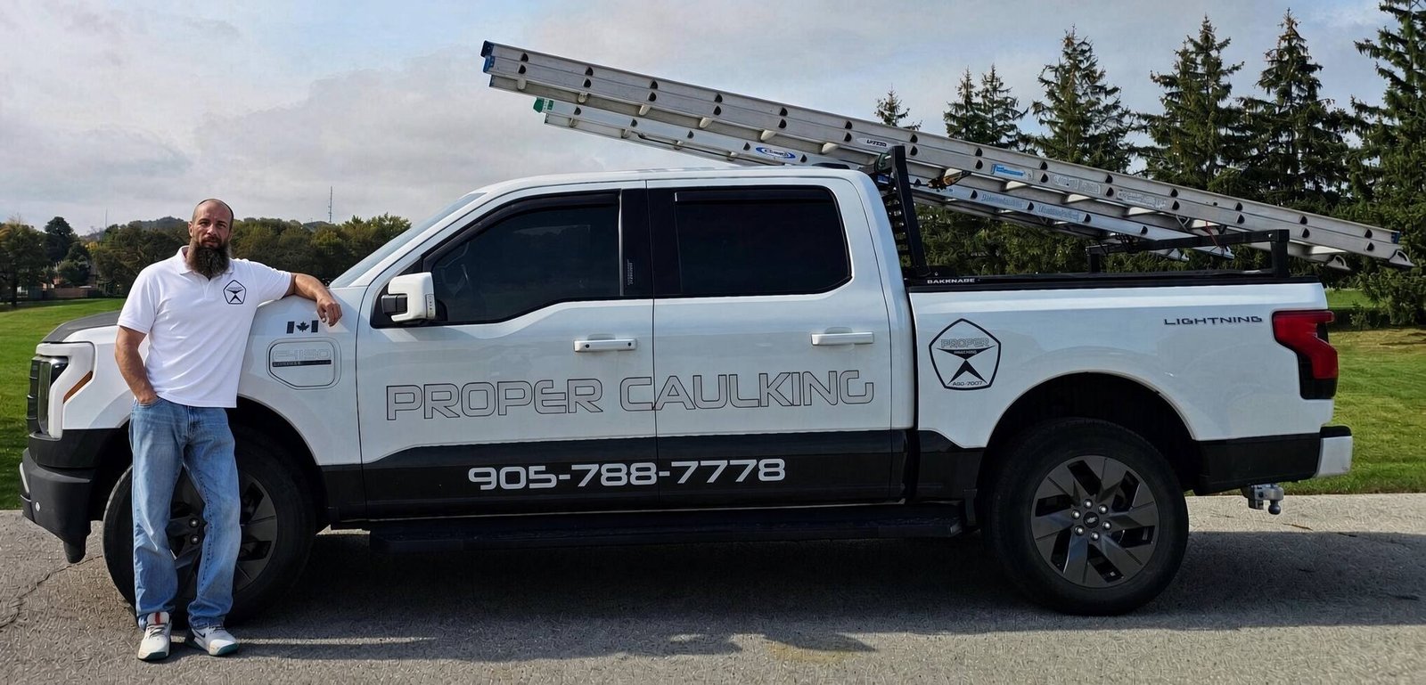 Oleg standing proudly beside his wrapped company trade truck displaying the Proper Caulking logo in Burlington Ontario